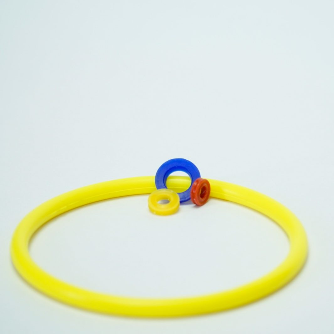 Gelber O-Ring mit drei weiteren kleinen Dichtungen in gelb, rot und blau (kundenspezifisch hergestellt)